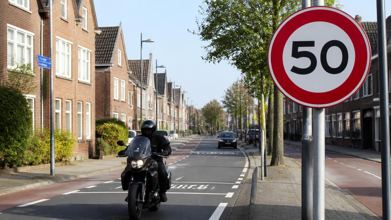 Motorrijder op weg binnen de bebouwde kom met bord 50 km/u