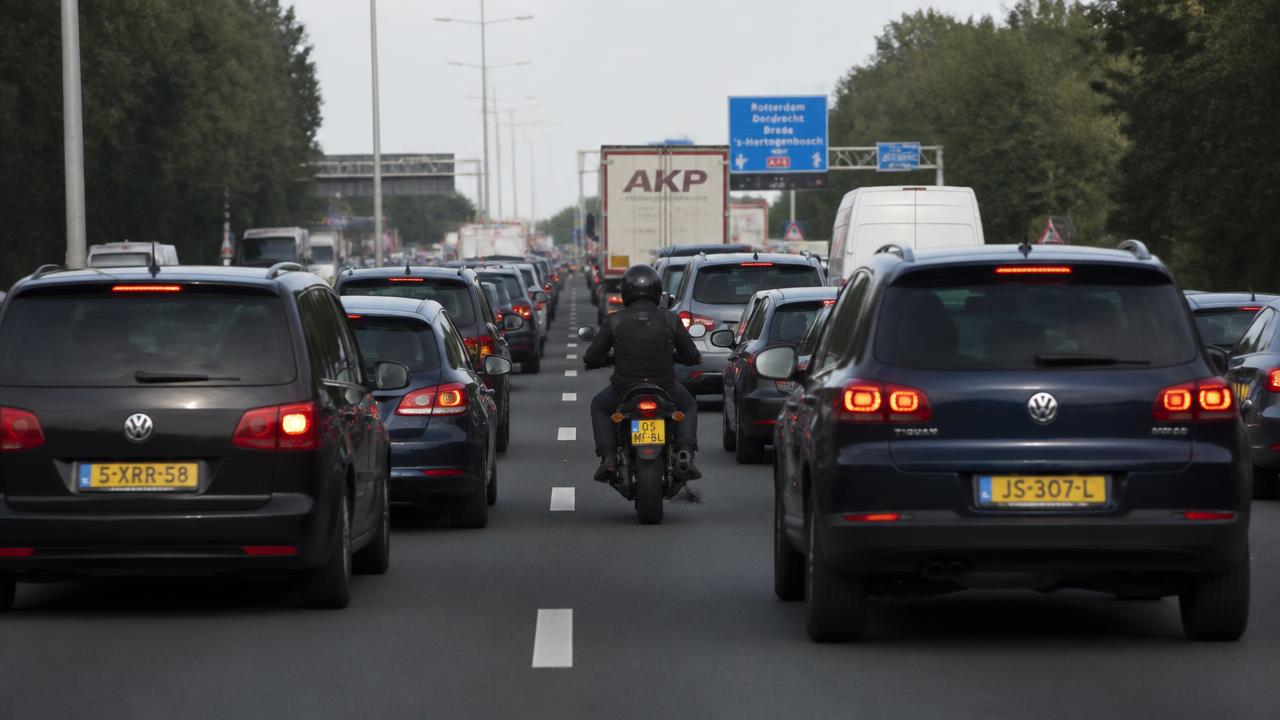 Motorrijder filtert rustig tussen twee rijstroken in de file
