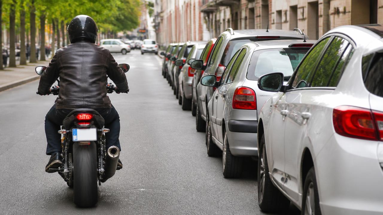 Motorrijder houdt afstand van geparkeerde auto's en de portierzone